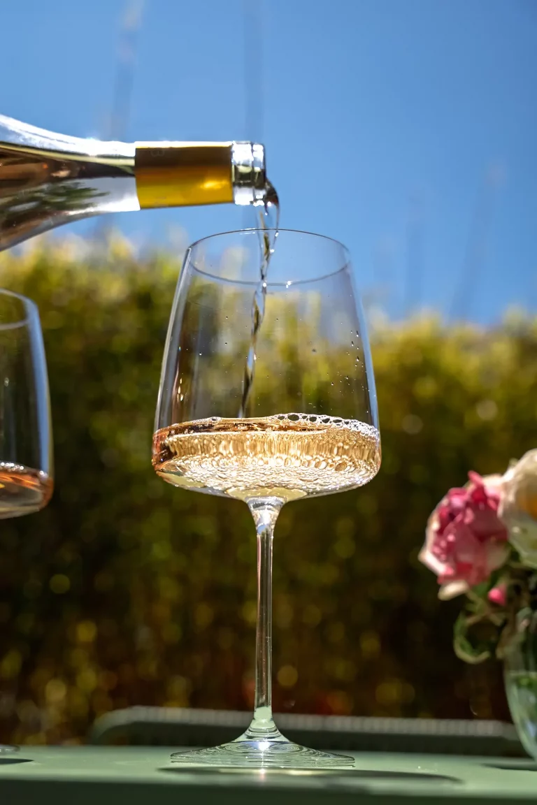 White wine being poured into a glass outdoors